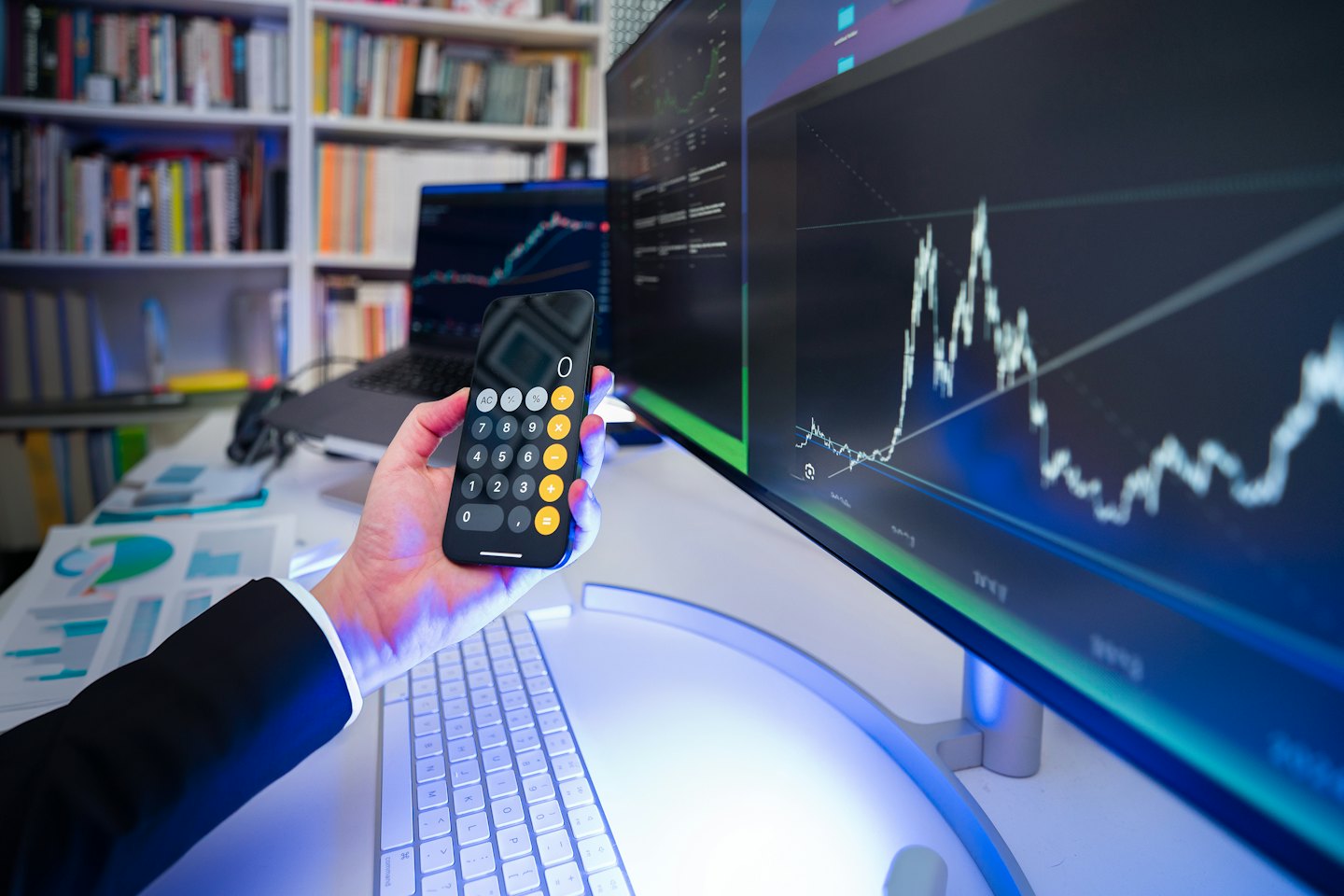 Osoba analizująca finanse za pomocą smartfona i komputera.